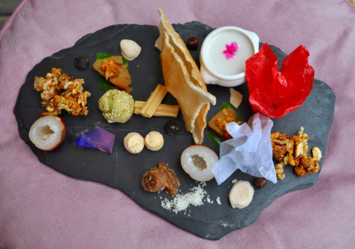 An assortment of traditional Thai desserts: pastries, fruits and sweet coconut soup garnished with edible flowers.