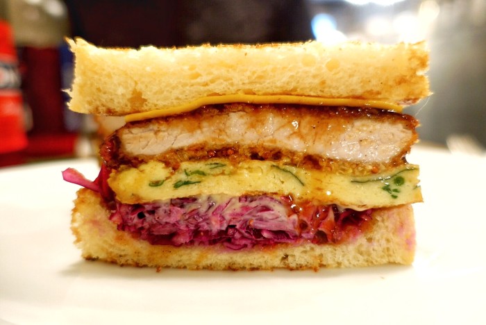 This epic Katsu Sando is piled high with a crispy pork cutlet, cloud-like yet perfectly dense vegetable omelet, cabbage slaw, homemade mayo, Dijon mustard, Mimolette cheese and tonkatsu sauce.
