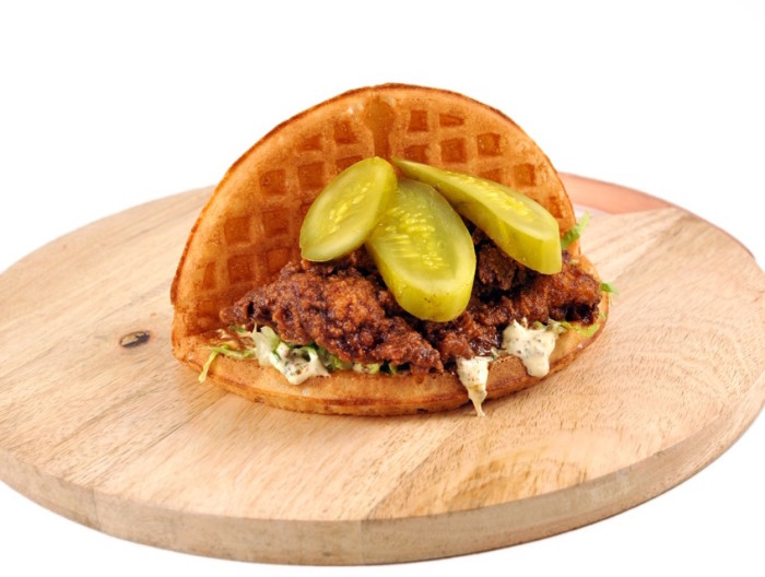 This handheld treat tucks a spicy chicken cutlet, shredded lettuce and pickles between a crispy waffle. (Photo credit: Bruxie)