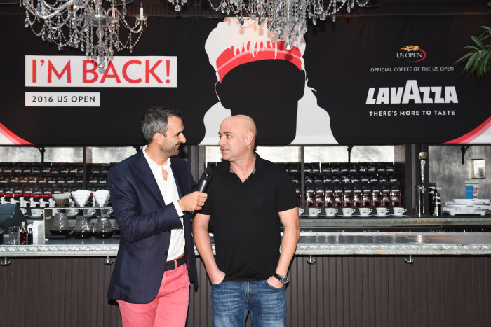 Andre Agassi (right) chats with coffee mogul Marco Lavazza (left) in front of a large silhouette of the ex-tennis star's former flamboyant hairstyle during the 2016 U.S. Open in NYC. (Photo: BFA/Leandro Justen)