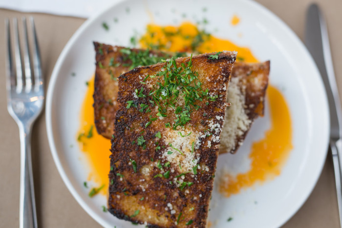 Roustabout's garlic bread features thick, crusty slabs of house made bread bathed in garlic butter and Calabrian chile-infused oil. (Photo credit: Roustabout)