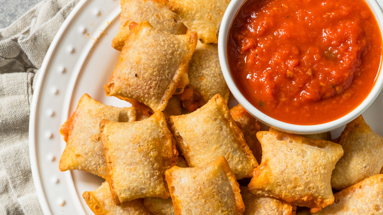 Plate of crispy pizza rolls with a cup of marinara dipping sauce
