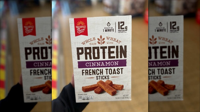 A hand holds up a package of Breakfast Best Protein Cinnamon French Toast Sticks