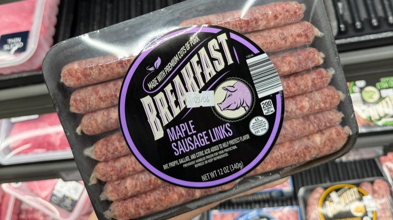 A hand holds up a package of Aldi's Maple Breakfast Sausage Links