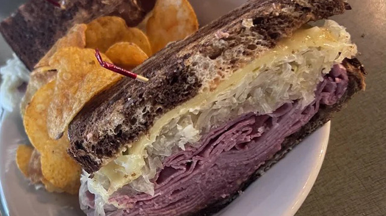 The inside of half a Reuben from Jason's Deli, with potato chips, on a white plate
