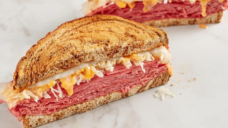 A McAlister's Deli Reuben on marble rye bread sits on a marble counter.