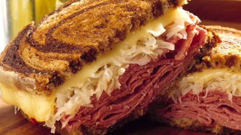 Two halves of a Mr. Pickles Reuben on marble rye bread sit on top of each other.