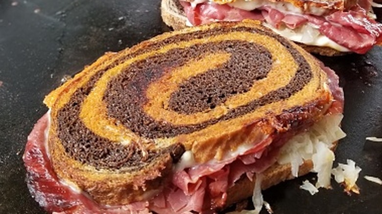 Reuben sandwiches on marble rye cook on a griddle.