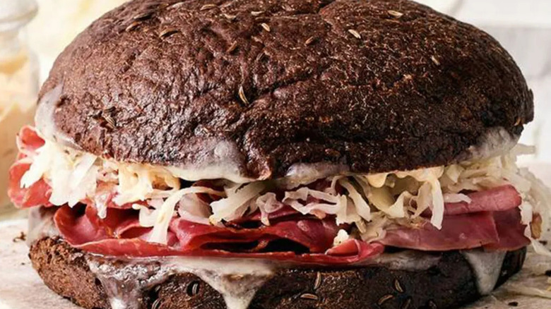 A Schlotzky's pastrami reuben sandwich on rye is pictured close up.