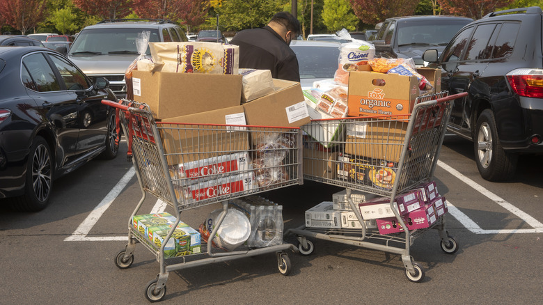Man loading two overflowing shopping carts of goods into car