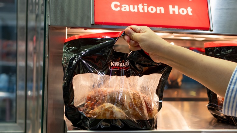 Hand selecting Costco Rotisserie Chicken from hot display