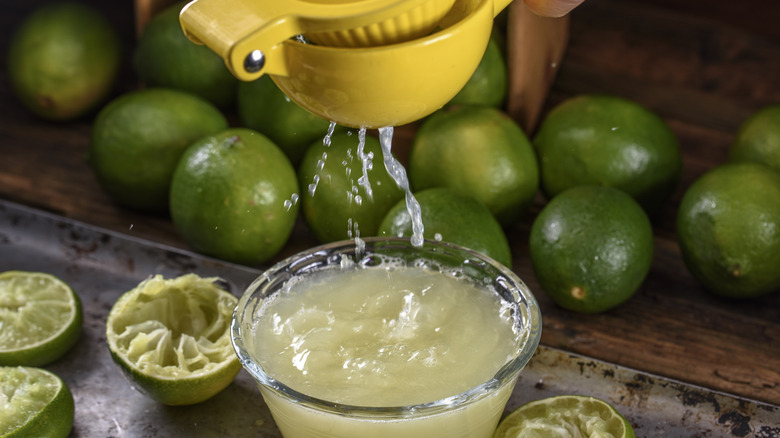 Juicing lime halves with small dish of fresh lime juice