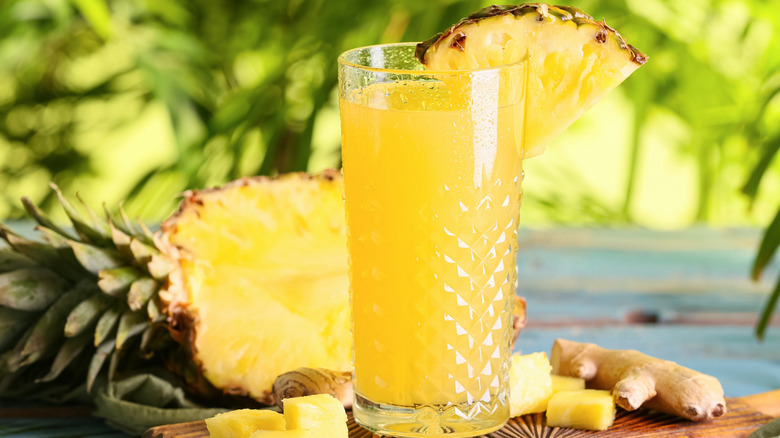 Glass of pineapple juice with fresh pineapple wedge garnish