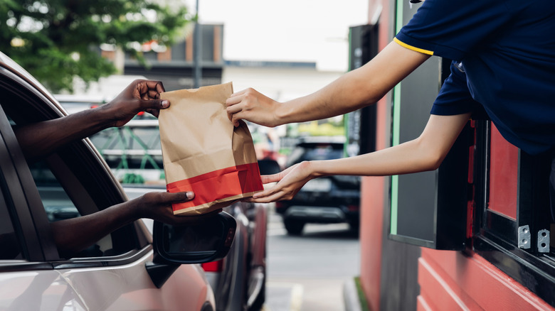 Someone receives drive-thru food.
