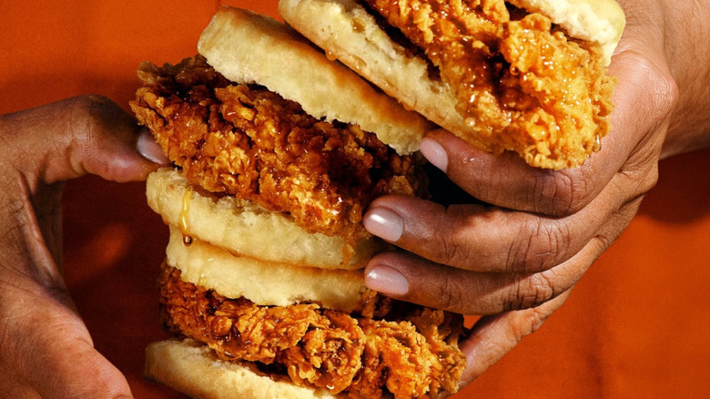 Hands hold several Honey Chicken Biscuits.