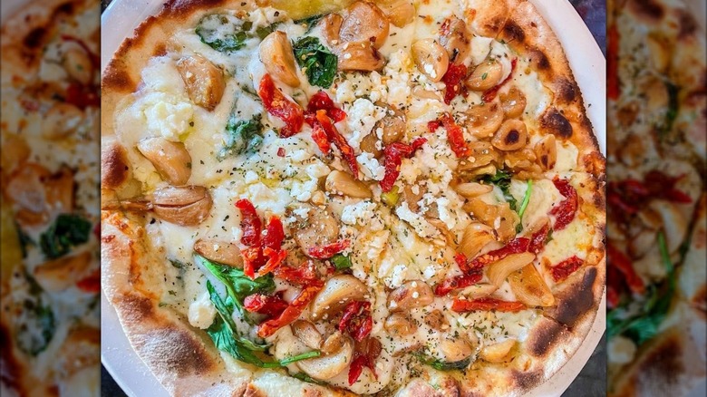 Closeup of a roasted garlic pizza with sundried tomatoes and basil