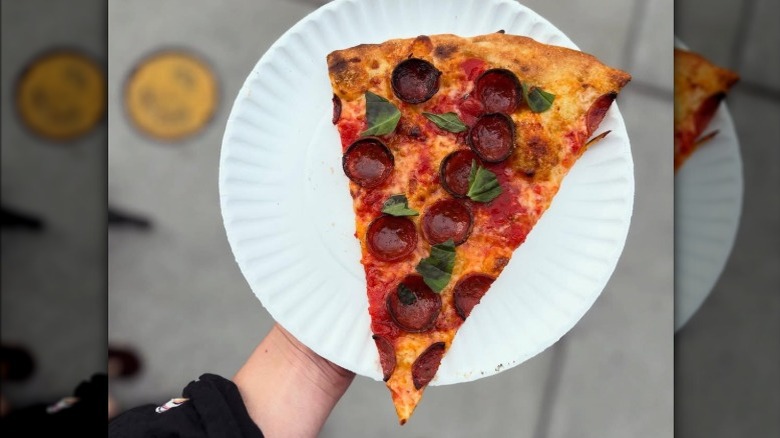 An oversized slice of pizza with cupped pepperoni, basil, and hot honey at St. Pizza in New Orleans, LA