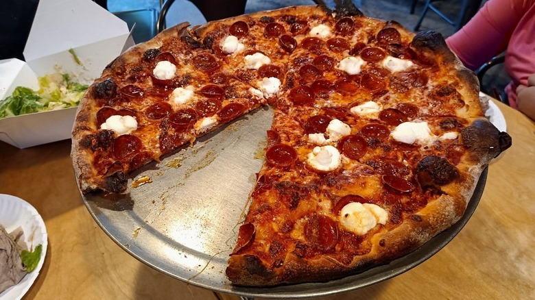 A pepperoni and ricotta pizza sits on a metal plate at Zee's Pizzeria in New Orleans, LA