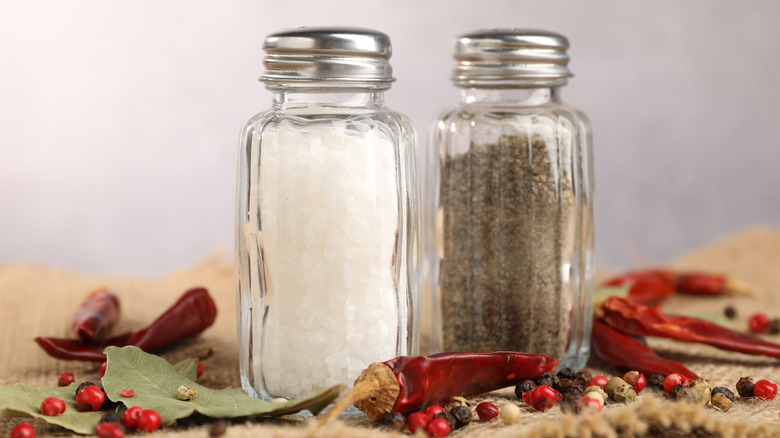 Salt and pepper shakers surrounded by dried peppers