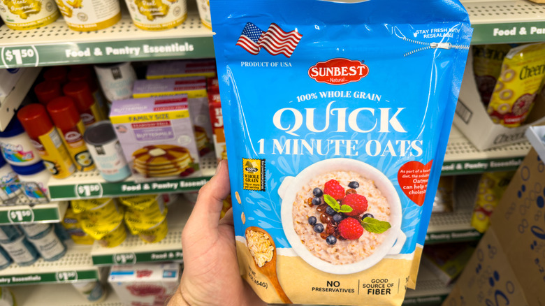 Hand holding a package of Sunbest 100% Whole Grain Quick 1 Minute Oats
