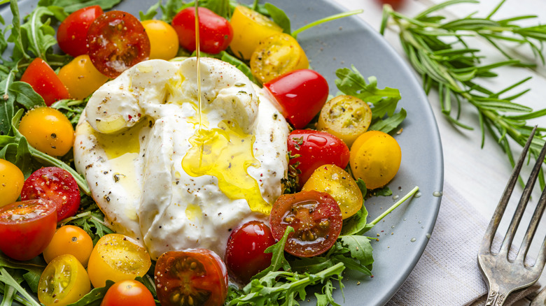 Ball of burrata on salad greens with olive oil