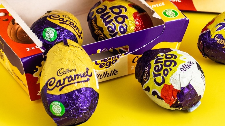 Cadbury creme eggs in a box and placed on a yellow surface