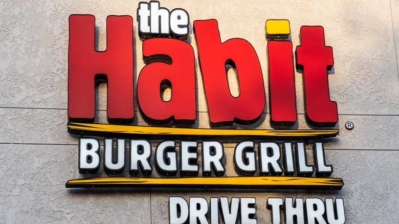 Habit drive thru sign affixed to a stucco wall