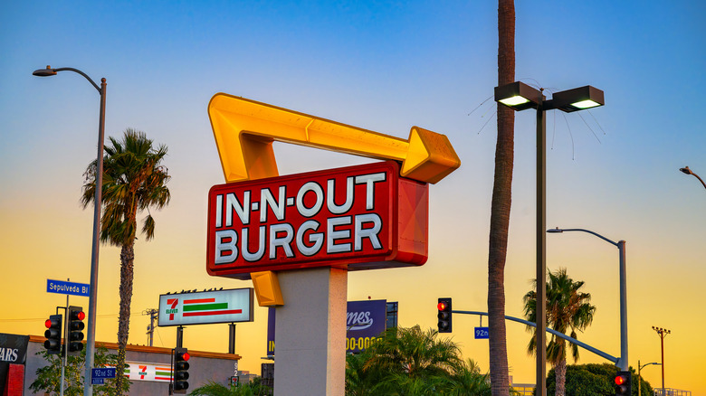 Sunset behind a glowing In-N-Out Buger arrow sign