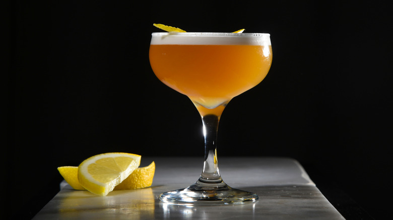 cocktail glass with foam top and lemon garnish