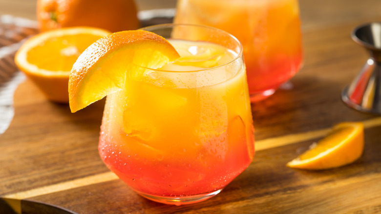 red and yellow layered cocktail with orange wedge