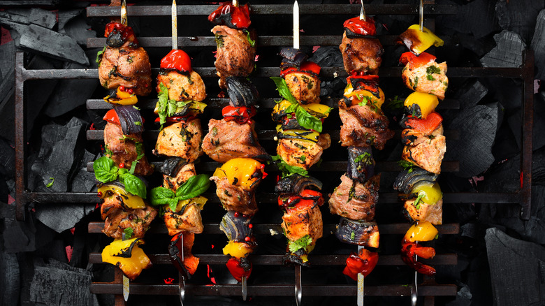 A row of kabobs are lined up on a charcoal grill