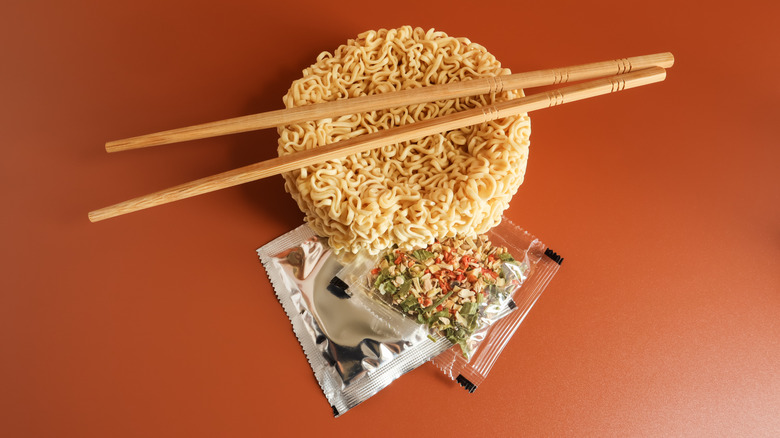 Uncooked instant ramen with seasoning packets and chopsticks