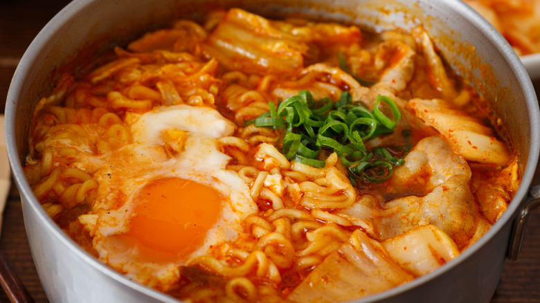 Large metal pot of kimchi ramen with a fried egg on top