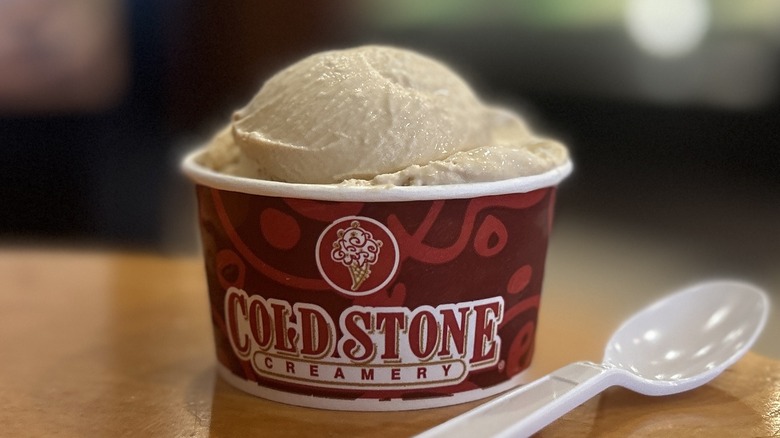 Cold Stone Coffee Ice Cream in a small cup on a wooden table with a white spoon placed to the left of it