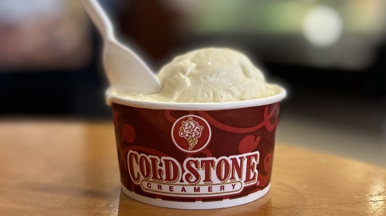 Cold Stone Cake Batter Ice Cream in a small cup on a wood table with a white spoon