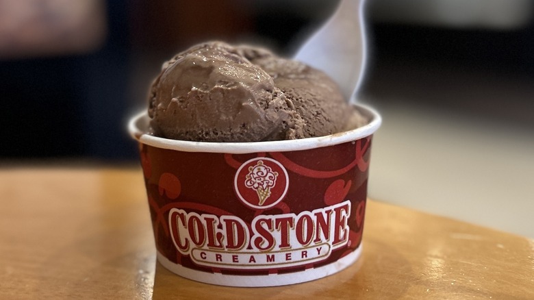 Cold Stone Chocolate Ice Cream in a small cup on a wooden table with a white spoon