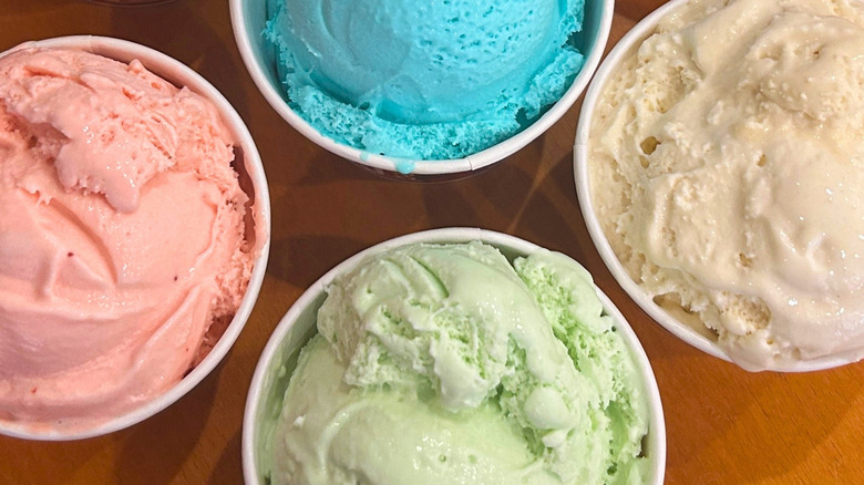 Top view of four separate cups of Cold Stone ice cream flavors, including Strawberry, Cotton Candy, Mint, and Cookie Dough