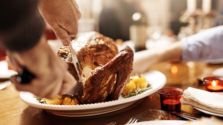 A closeup of someone carving a holiday turkey