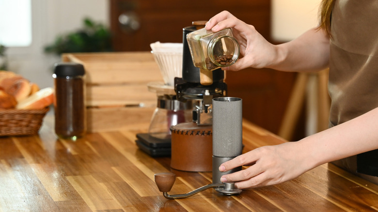 woman putting beans in a coffee grinder