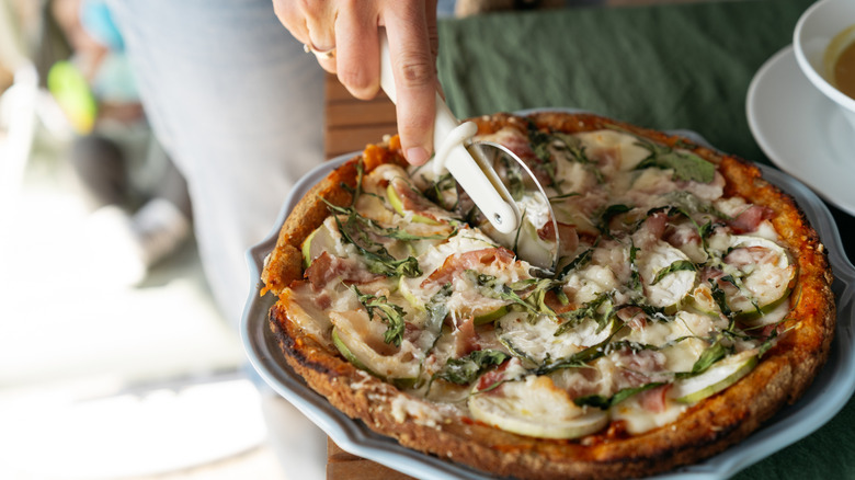 A man cutting into a pizza, the pizza has a homemade low carb pizza crust