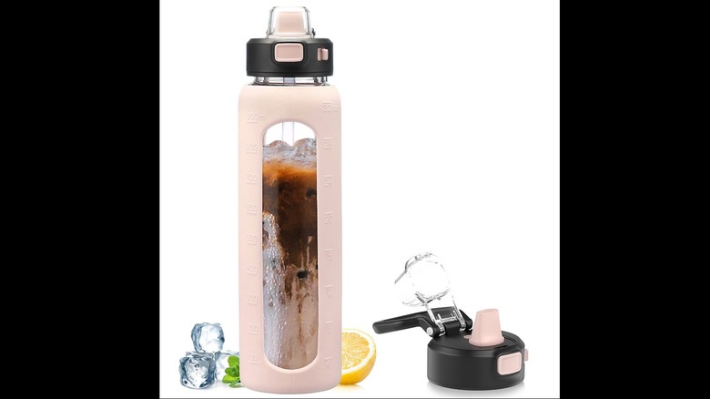 A glass and pink silicone water bottle with iced coffee inside