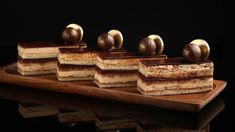 Slices of opera cake lined up on a wooden board