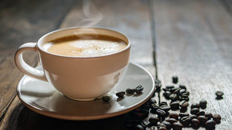 Mug of coffee on saucer with espresso beans
