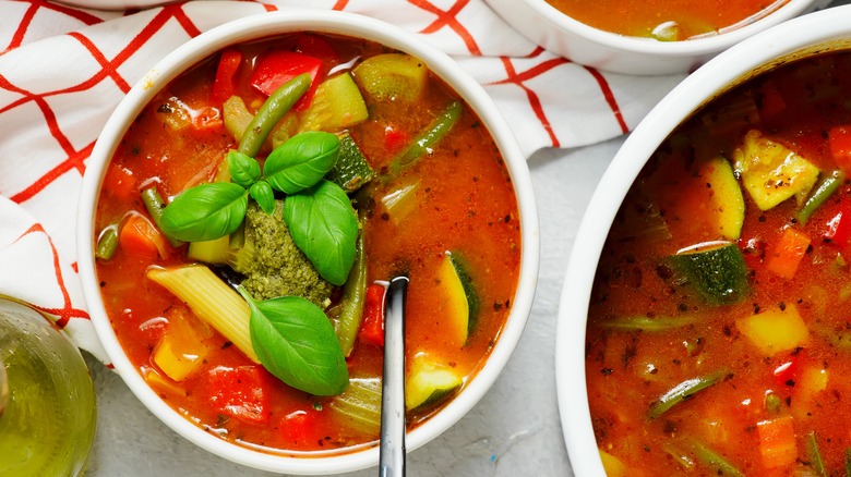 Bowl of minestrone soup with pesto and fresh basil on top