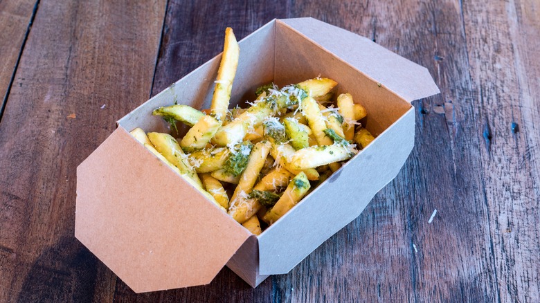 To-go box of French fries with pesto and parmesan