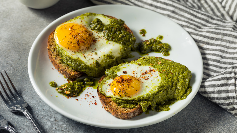 Two pieces of toast topped with pesto and a fried egg
