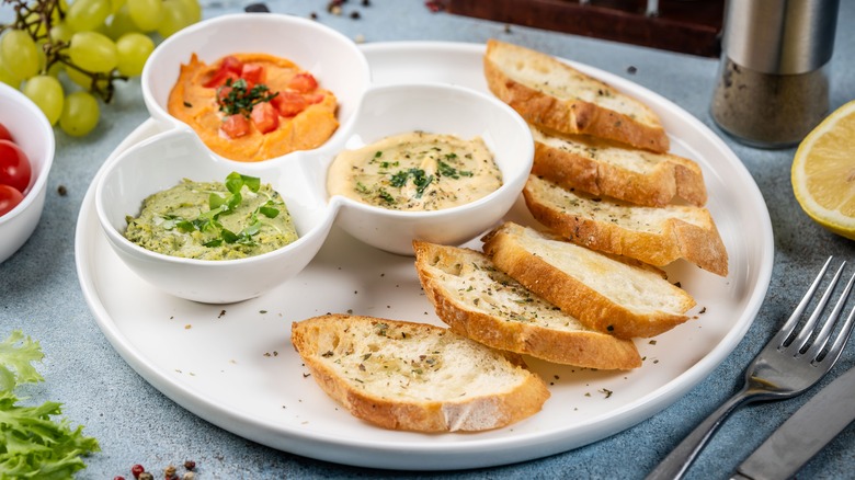 Assorted dips on a plate with sliced French bread