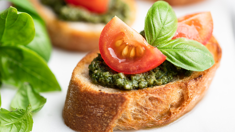 Slice of pesto bruschetta with fresh tomatoes and basil