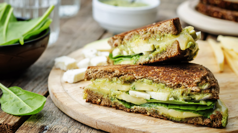 Side view of a grilled sandwich with pesto, spinach, avocado, and cheese