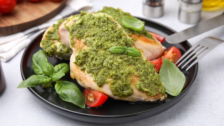 Plate with two chicken breasts smothered with pesto